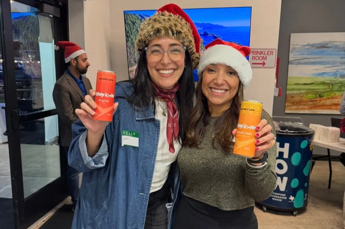 Two attendees showing canned drinks at a holiday gathering