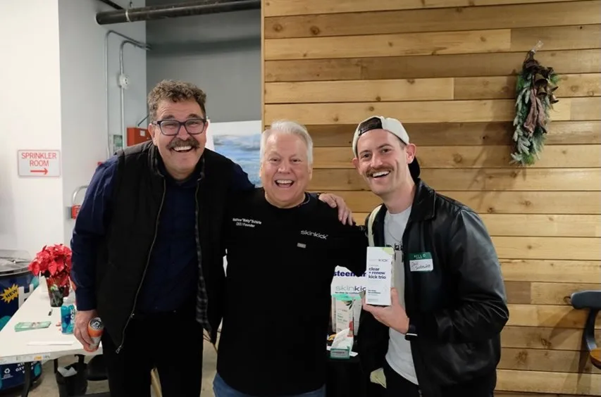 Three attendees smiling together at a holiday gathering