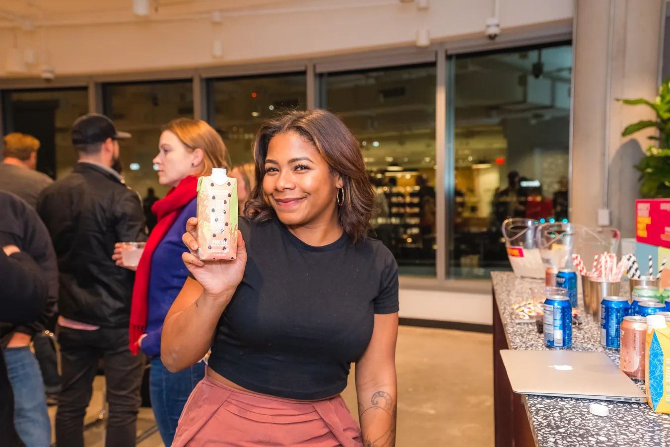 A brand representative holding a product beside a sampling table