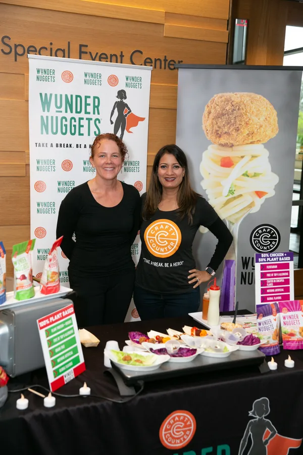 Two exhibitors behind a sampling table at Pitch Slam
